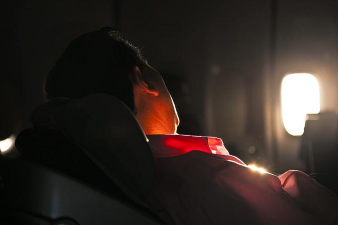 सूर्योदय में एक विमान के सीट में आदमी सो